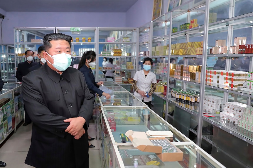 Men in black suits inside pharmacy.