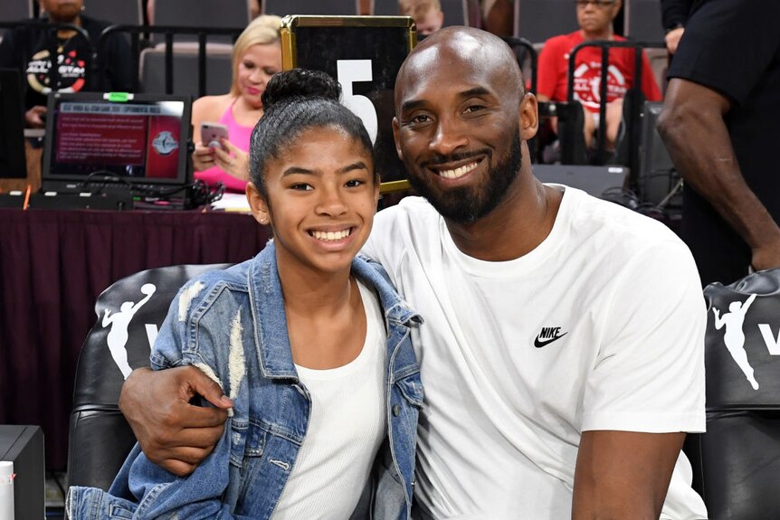 gianna and kobe bryant smile arm in arm courtside at a basketball game