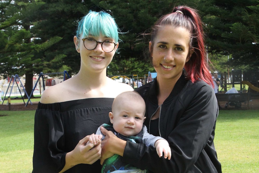 Two women hold a baby.