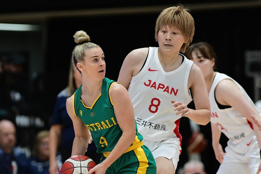 Stephanie Reid bounces the basketball while a defender from Japan tries to block her.
