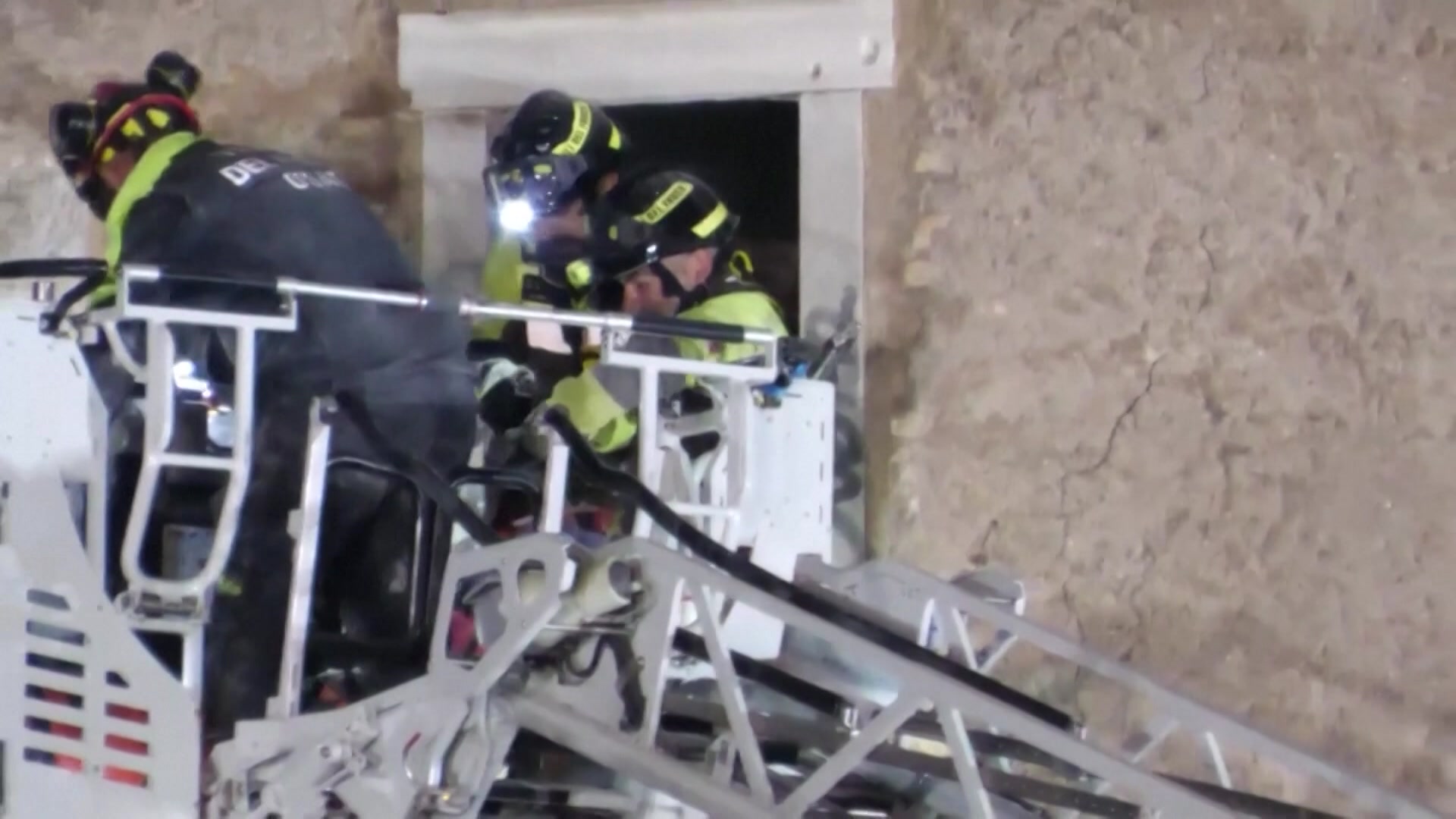 Rescue workers in protective gear place a man on an elevated platform 