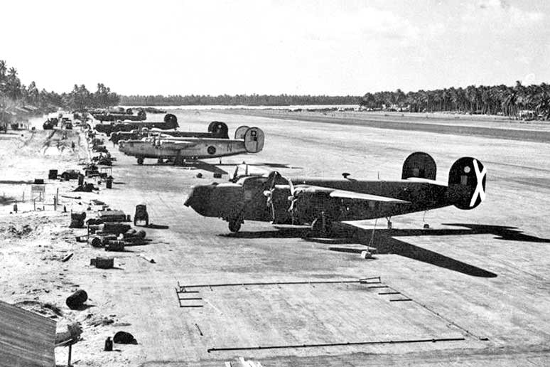 A black and white photo of bomber aircraft parked at the edge of a runway.
