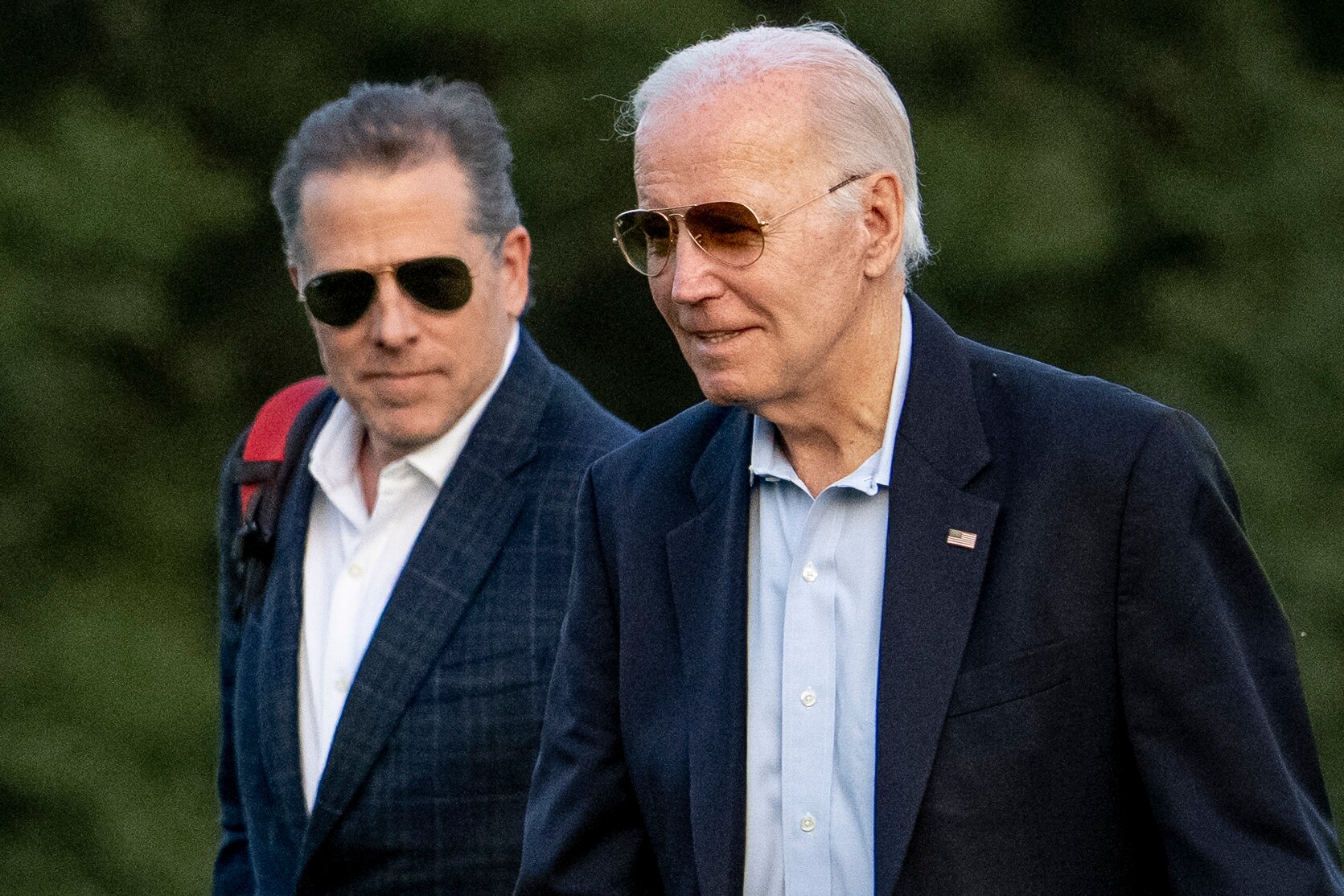 Joe Biden and Hunter Biden, pictured outdoors, wear dark jackets and sunglasses.