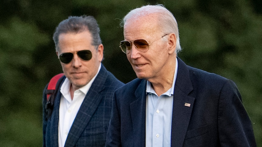 Joe Biden and Hunter Biden, pictured outdoors, wear dark jackets and sunglasses.
