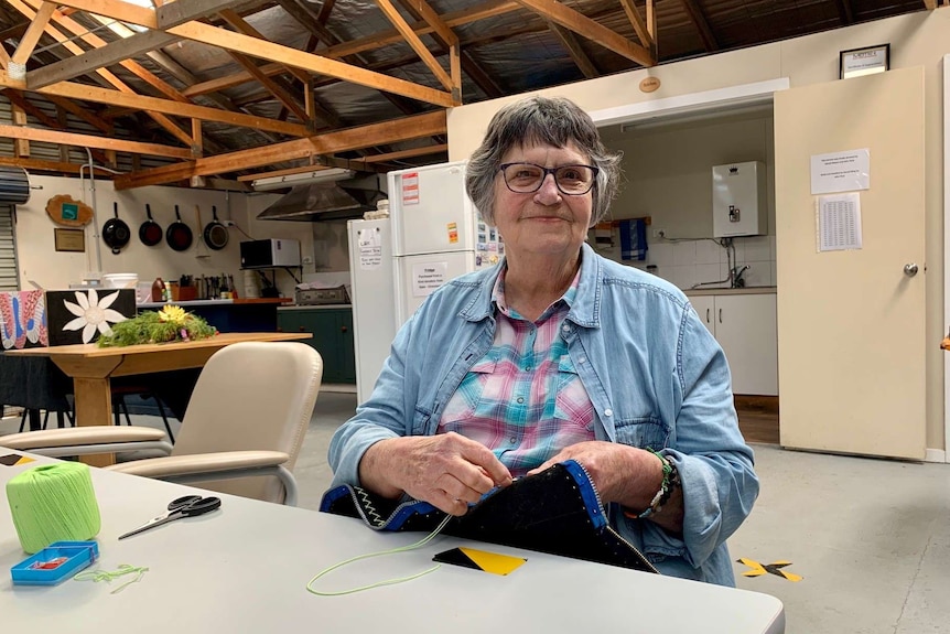 A woman sat sewing at at table