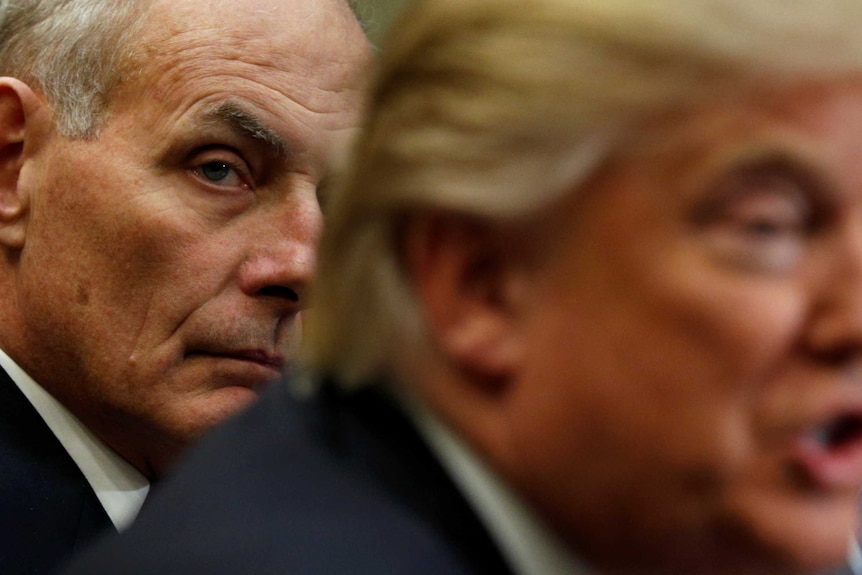 John Kelly sits behind and listens to Donald Trump speak during a meeting.