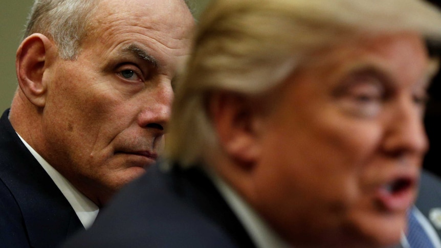 John Kelly sits behind and listens to Donald Trump speak during a meeting.