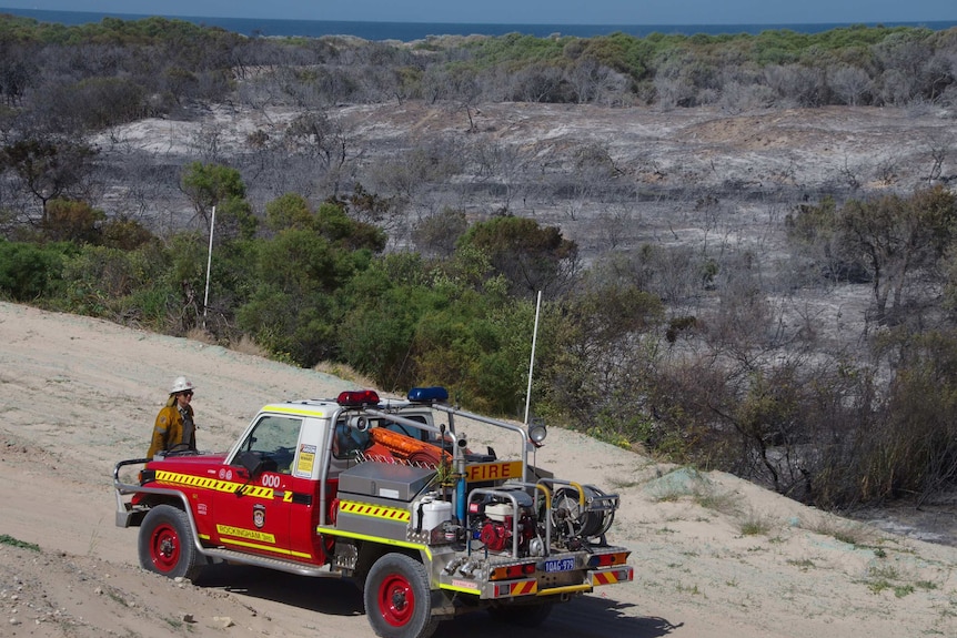A fire appliance parked on a sand dune near a burnt out patch of land at Secret Harbour.