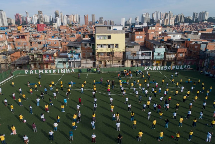 People stand spaced out on a football field in Paraisopolis