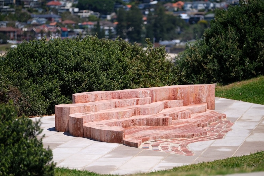 a piece of artwork made out of stone sits on a cliff besides the ocean