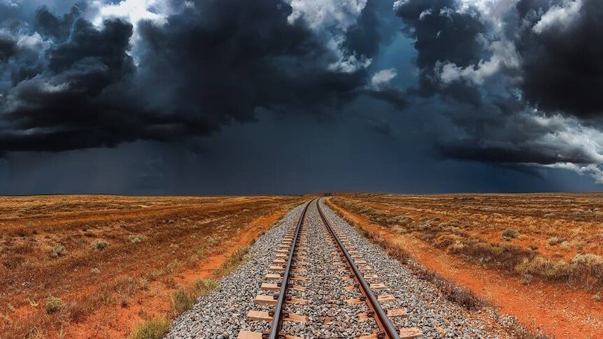 Dark storm clouds gather over a train line.