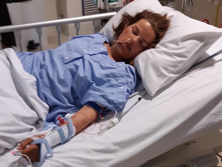 A young woman lying unconscious in a hospital bed