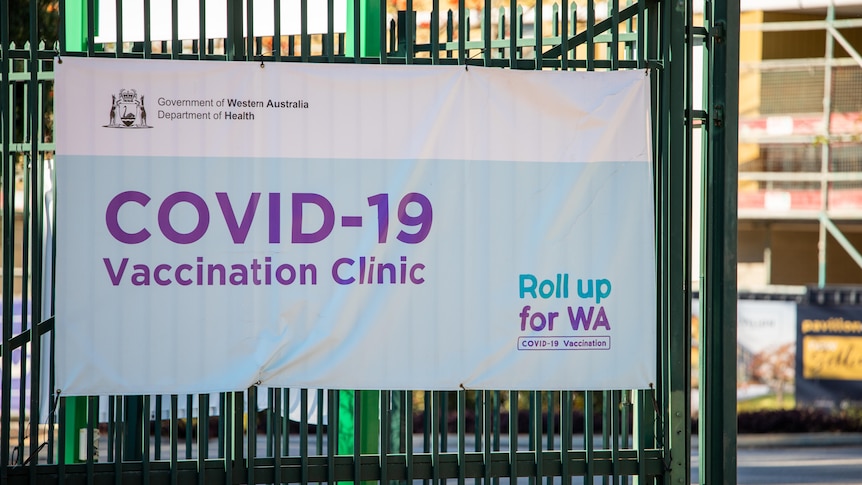 A sign hanging on a gate reading 'COVID-19 Vaccination Clinic'.