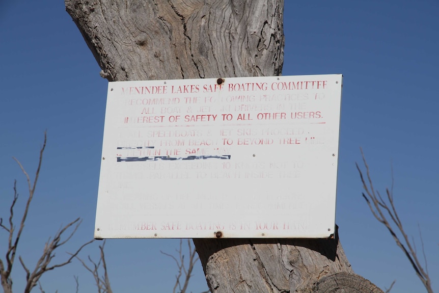 A faded sign from the Menindee Lakes Safe Boating Committee attached to a tree near the Lake Menindee foreshore.