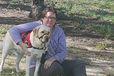 Murrianna Reese sitting on the grass with her arm around her dog Hunter