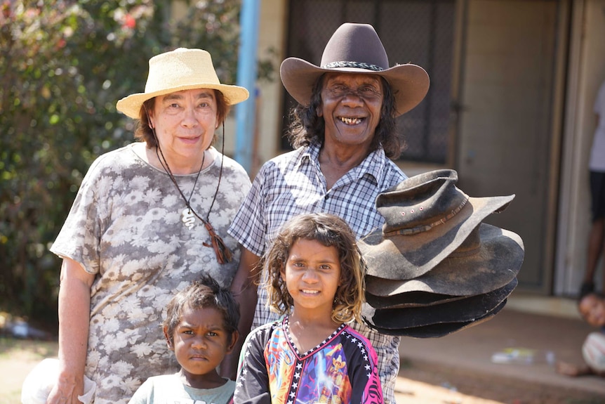 An older woman and older man pose for a photograph with two children.