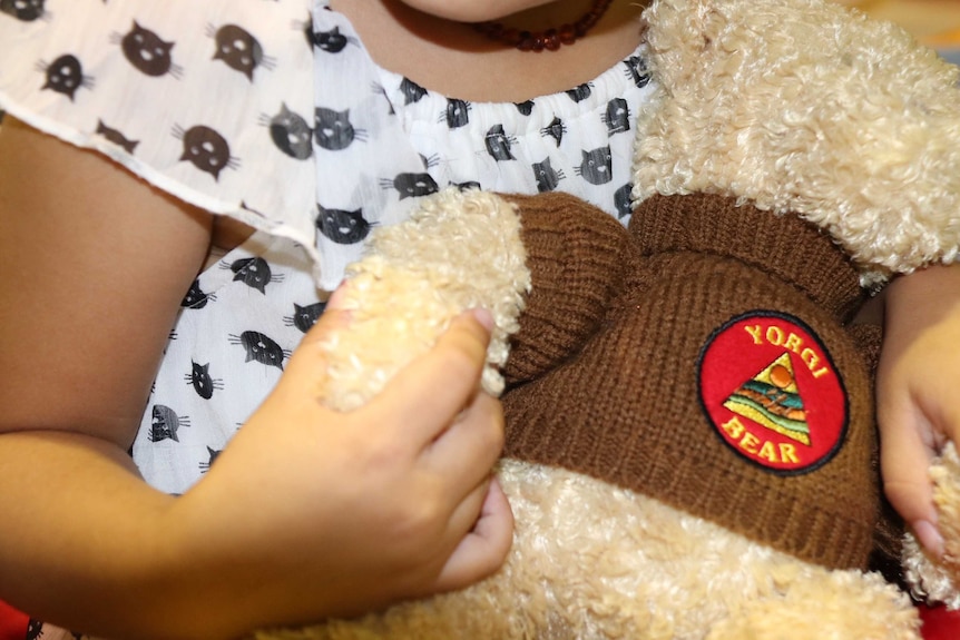 An unidentified child holding a teddy bear.