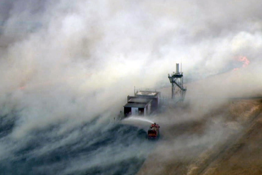 A fire tanker sprays a fire near a tower in a field near Pearce airbase.