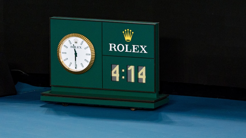 A picture of a clock on a tennis court showing 11:30 at night, next to a sign showing "4:14".