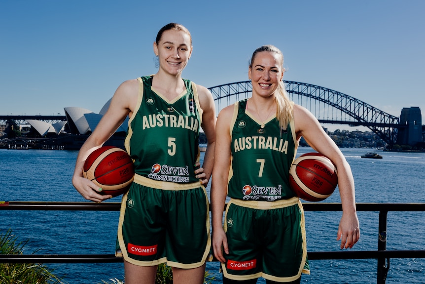 Australian Opals basketballers Darcee Garbin and Tess Madgen pose with basketballs , in front of the Sydney Harbour Bridge.