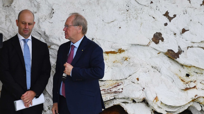 Todd Greenberg and Peter Beattie have a discussion in front of a rock wall