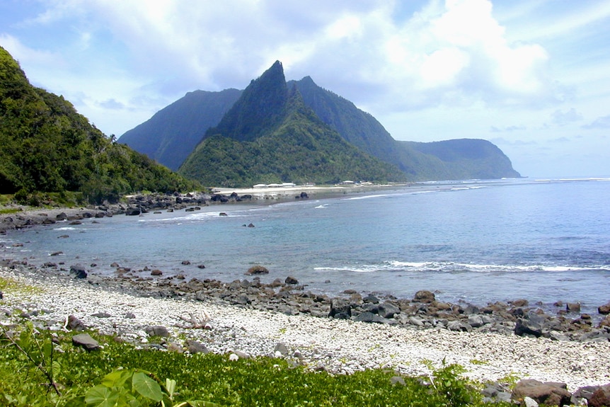 A shoreline on an island with a mountain in the background. 