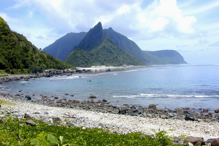 一座小岛上的海岸线，背景是一座山。 