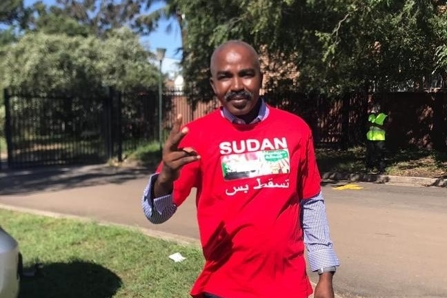 Sydney-based Sudanese asylum seeker Abdullah stands in a red t-shirt that reads Sudan.