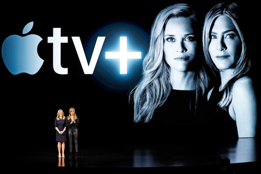 Reese Witherspoon and Jennifer Aniston on a stage talking about Apple TV