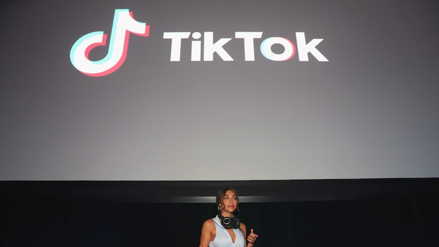 A woman DJs underneath a large screen that says TikTok.