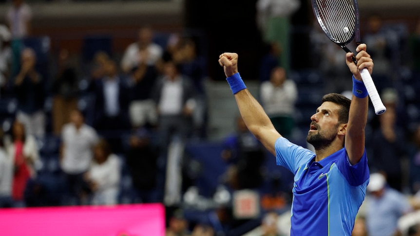 Man in blue pumps both firsts, one holding tennis racket 