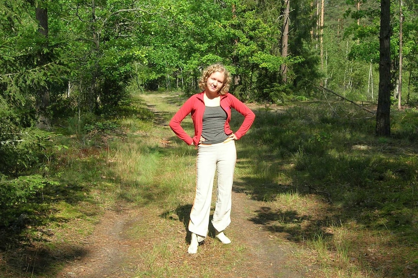 Svetlana Zhukova stands with hands on hips in a forest