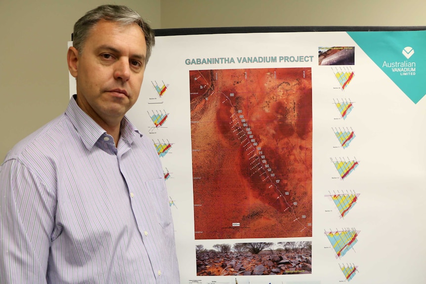 Vincent Algar stands in front of a map showing a vanadium deposit.