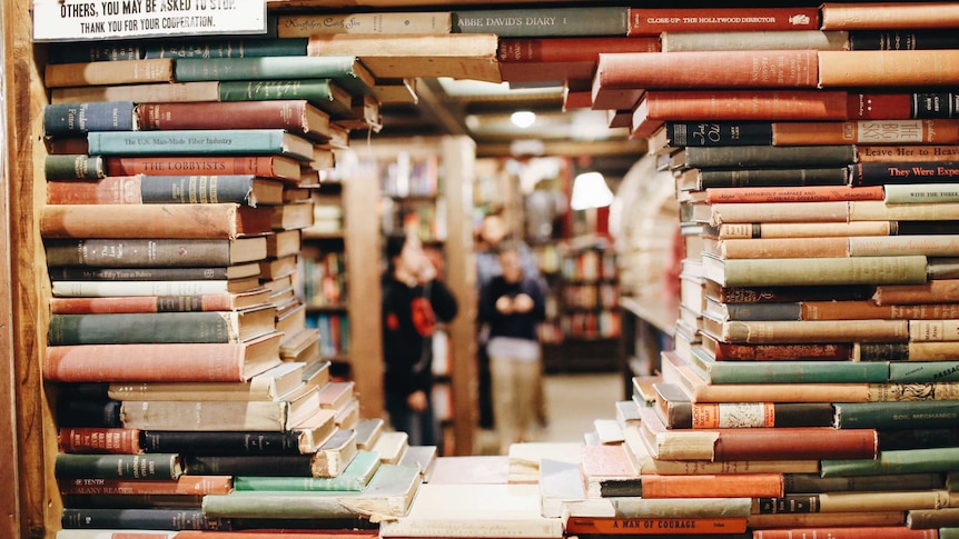 Books stacked to resemble brick wall, with round hole-shaped 'window' in the middle. Seems to be in a bookshop