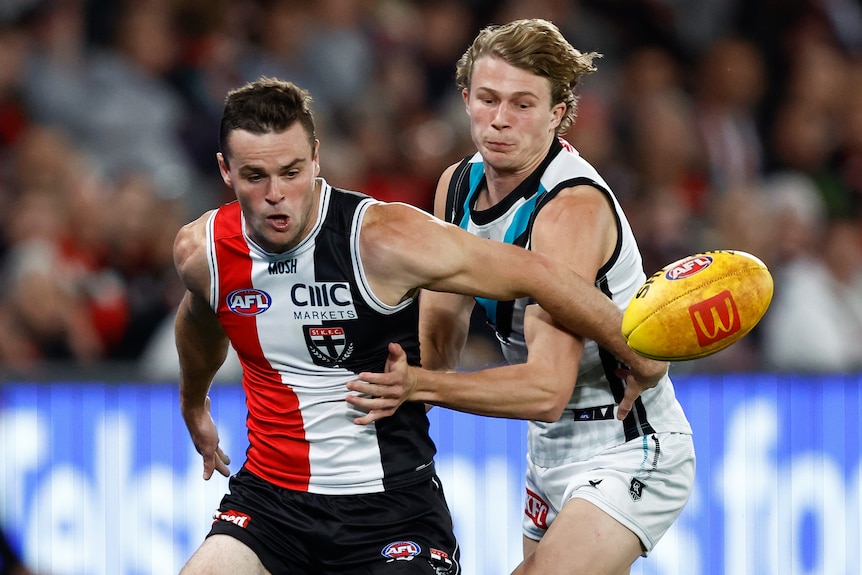 A St Kilda AFL player and a Port Adelaide opponent contest for the ball.
