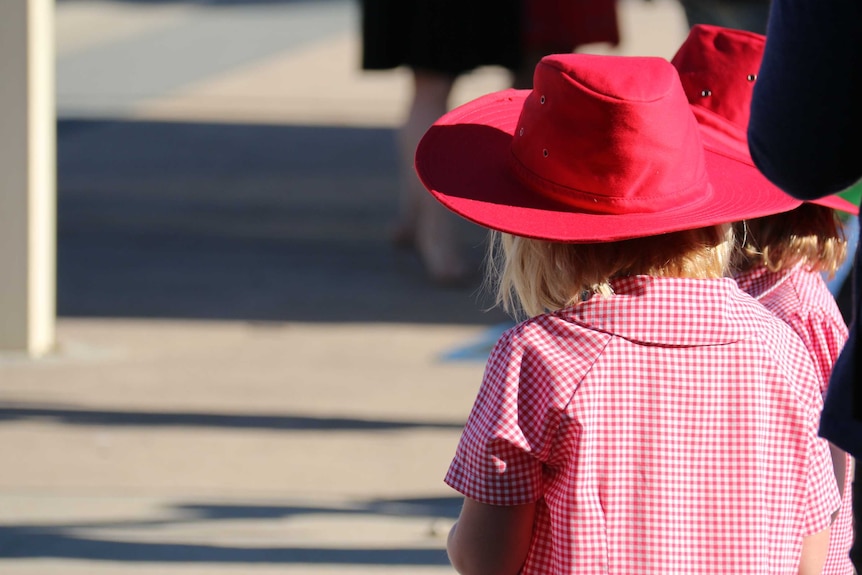 Two girls in broad brim hats and school uniforms.