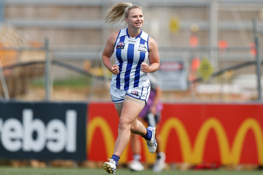 Daria Bannister runs and smiles after a goal during an AFLW match.