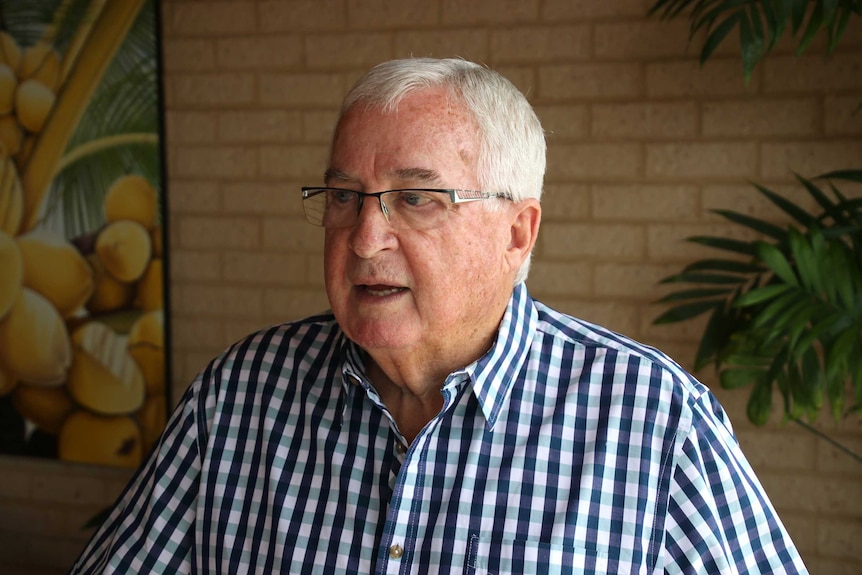 Mr Bowker speaks looking off to the right. He wears glasses and a checked shirt, standing in front of a wall.