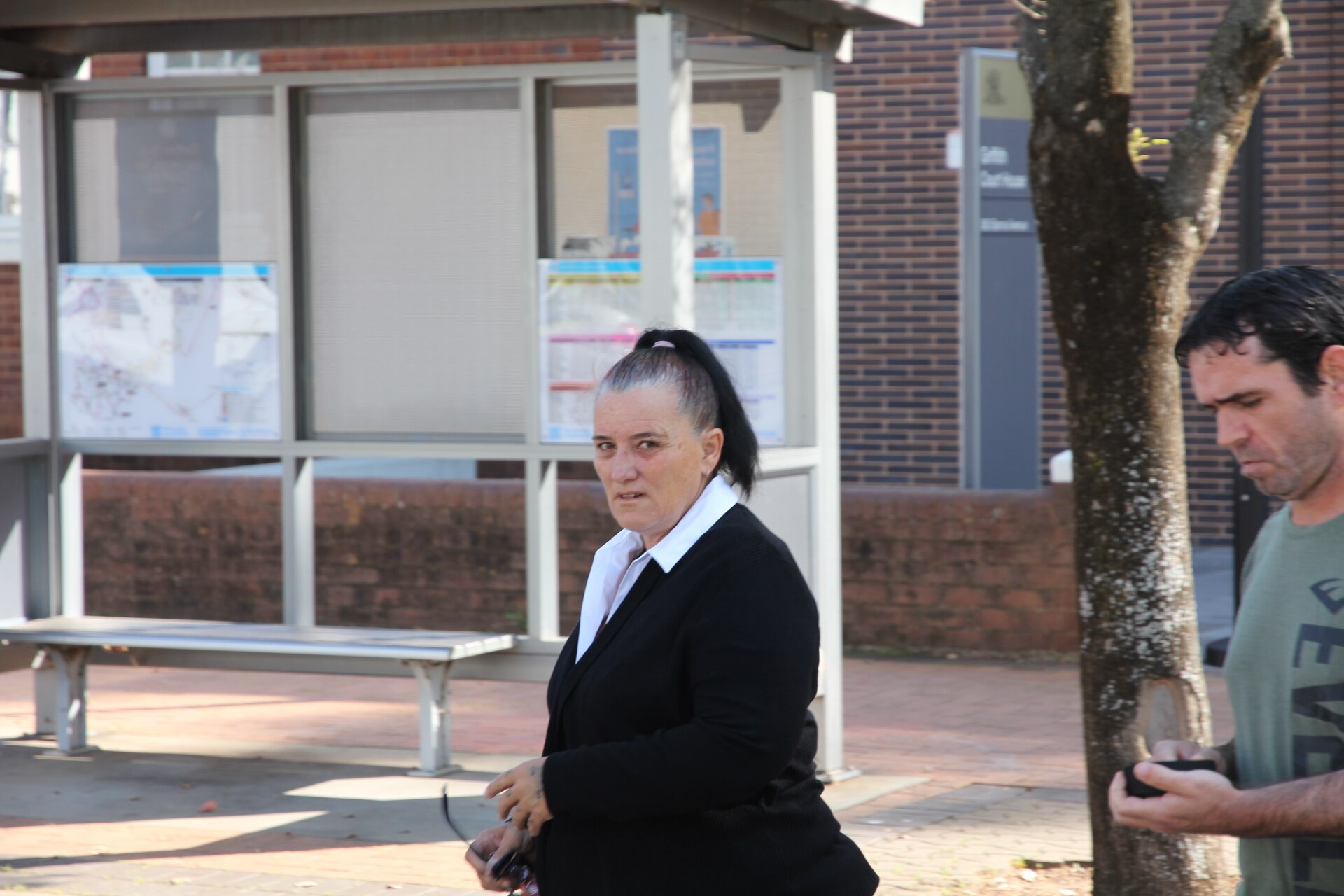 A woman with her black hair in a high ponytail walks across the street. 