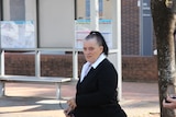 A woman with her black hair in a high ponytail walks across the street. 