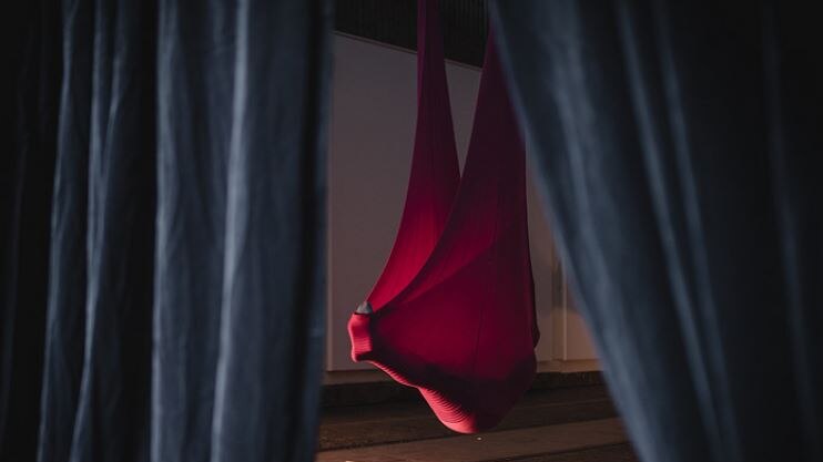 A person suspended in a red cloth in an art installation called 'Hypnopod'