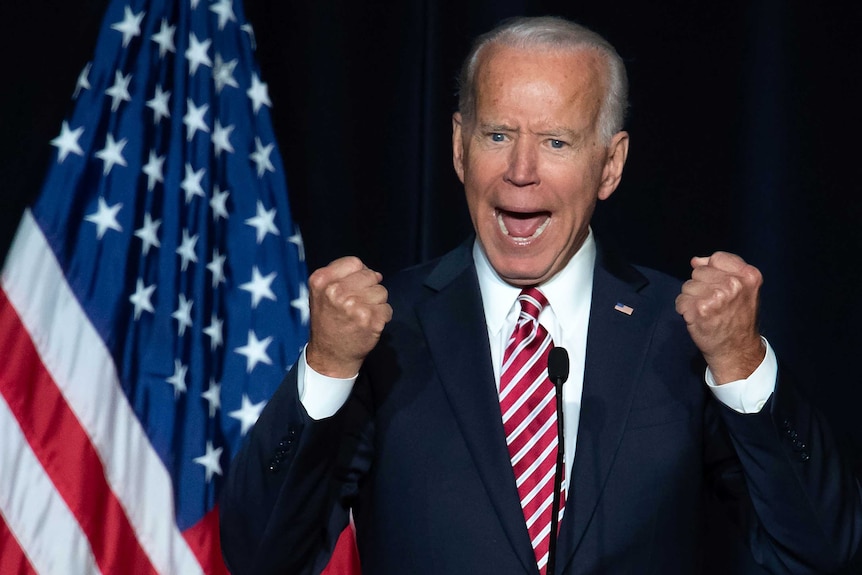 Joe Biden excitedly raises his fists while giving a speech.