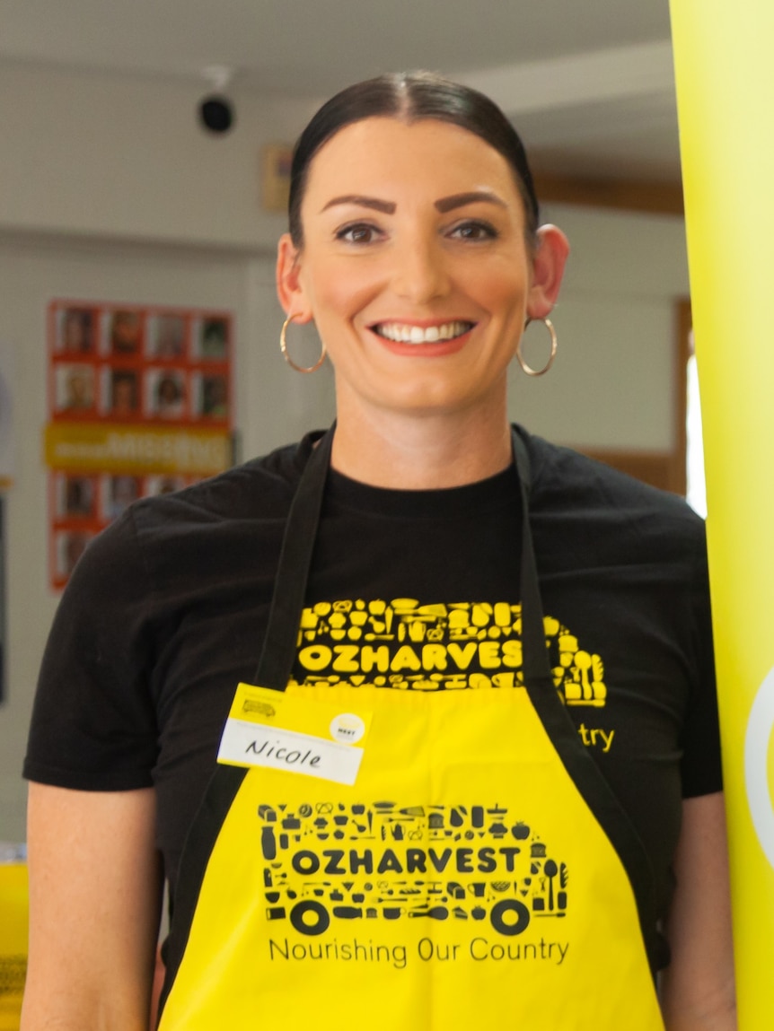 A woman in a yellow apron smiles