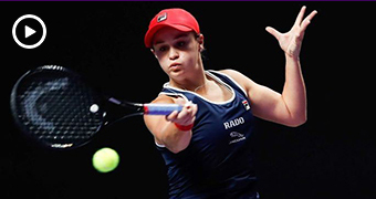 A woman with blue sports singlet and red cap swings a tennis racket with concentrated expression.