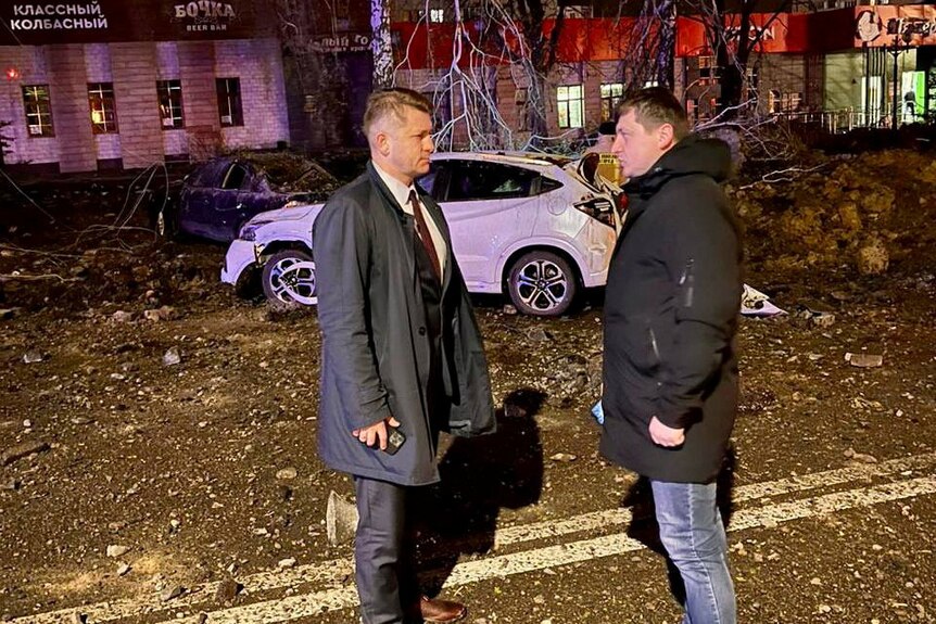 Valentin Demidov speaks to a man in a street in Belgorod near the sit of the accident