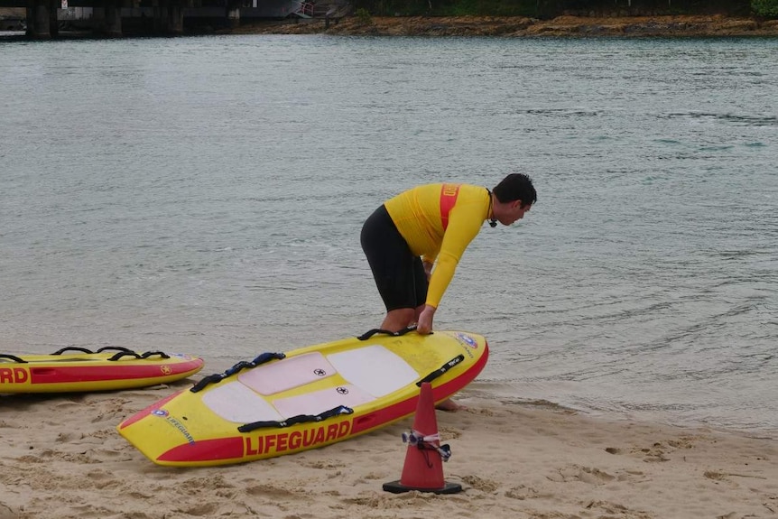 A surf lifesaver gets out his paddle board for a training exercise.