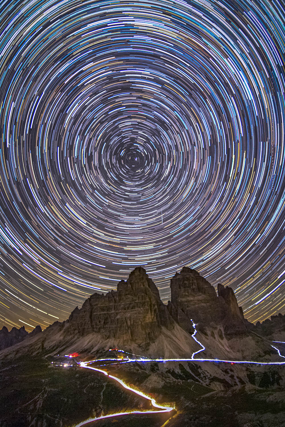 Circular star trails in the sky above a mountain peak.