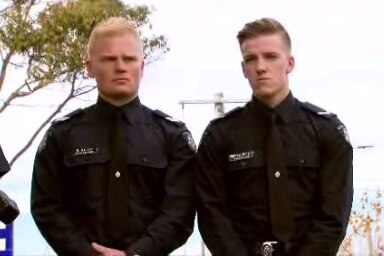 Two police officers standing side by side in uniform.