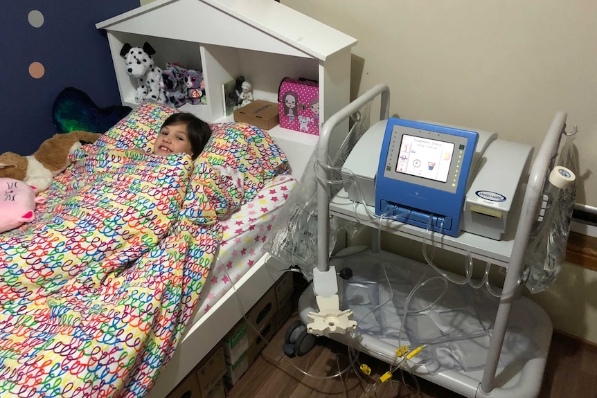 Lorelei lying in her bed, hooked up to her renal dialysis machine.