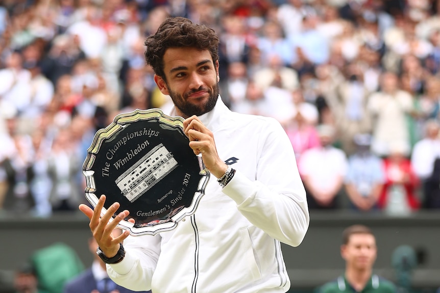 Mattero Berrettini sostiene un trofeo plateado y mira hacia un lado